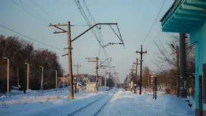 Augstsprieguma elektrības līnija pāri apsnigušam laukam Latvijas ziemas ainavā.