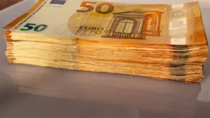 Kaudze ar 50 eiro banknotēm uz galda, simbolizējot ECB lēmumu ietekmi uz finansēm.