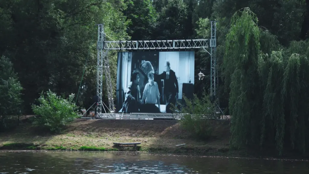 Liels āra ekrāns ar kino seansu gleznainā parka teritorijā pie ūdenskrātuves.