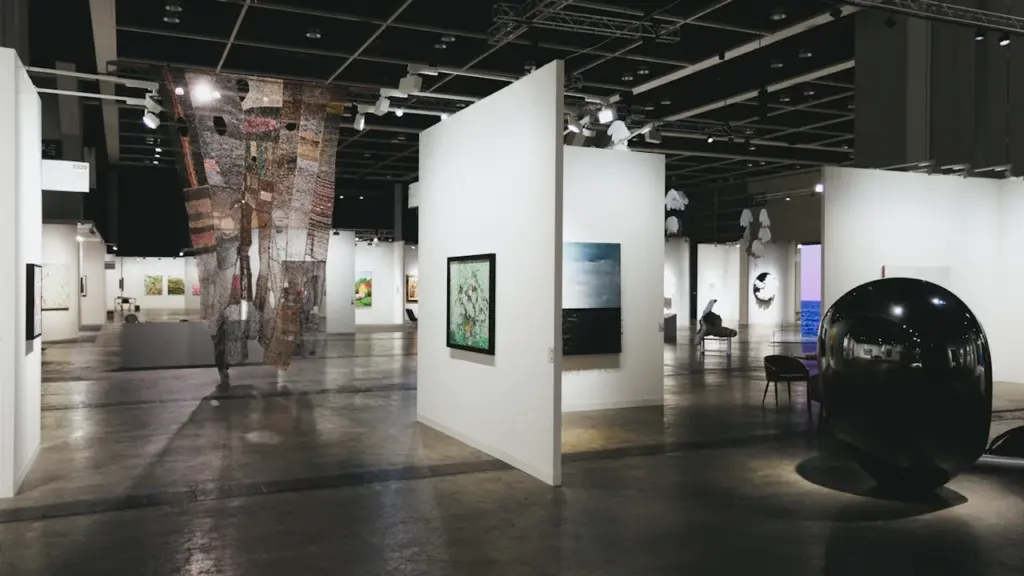 Plašas mākslas galerijas telpas ar gleznām un skulptūrām mūsdienīgā izstāžu zālē.