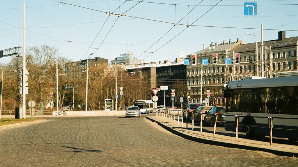Iela Rīgā ar sabiedrisko transportu un automašīnām saulainā dienas laikā.