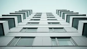 Daudzdzīvokļu mājas fasāde no apakšas, kas piemērota ēku siltināšanas un energoefektivitātes tēmai.