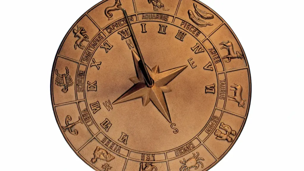 Bronzas zodiaka aplis ar iegravētām zīmēm un centrālo rādītāju uz balta fona.